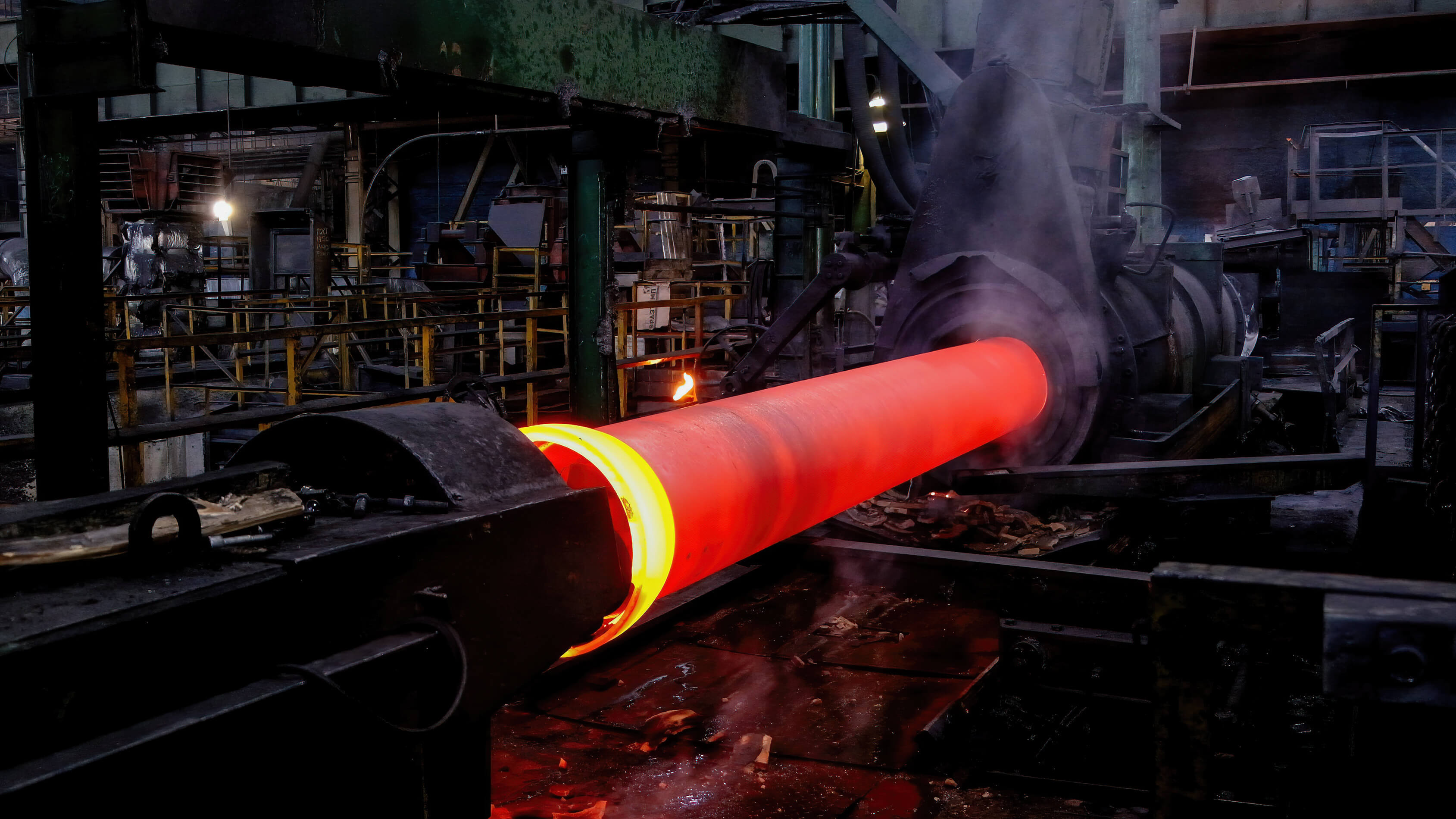 Tubo in acciaio incandescente durante il processo di laminazione a caldo in un impianto industriale