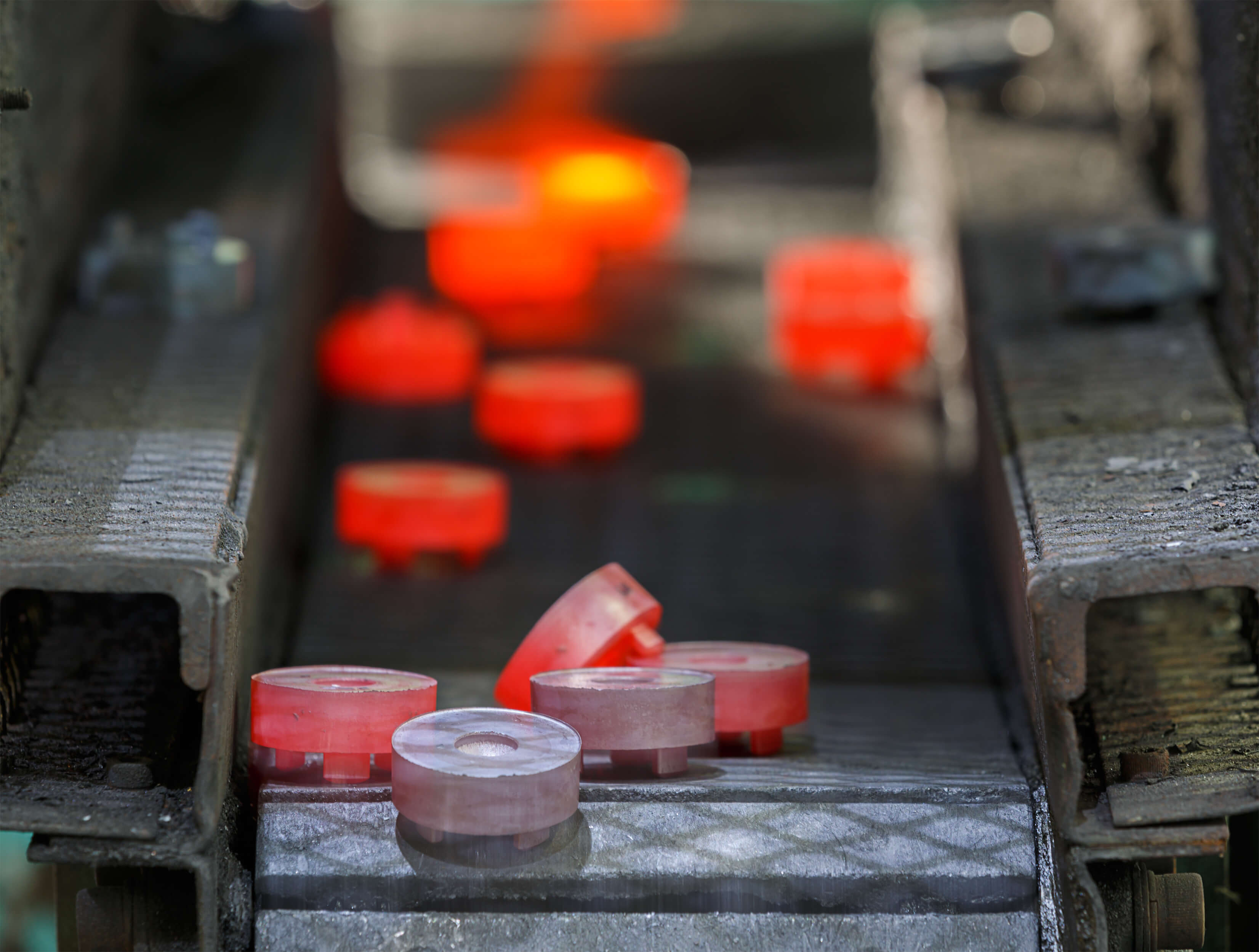 Componenti metallici incandescenti trasportati su un nastro in un impianto industriale