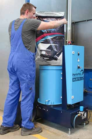 Operatore carica graniglia metallica in una macchina per la pallinatura industriale